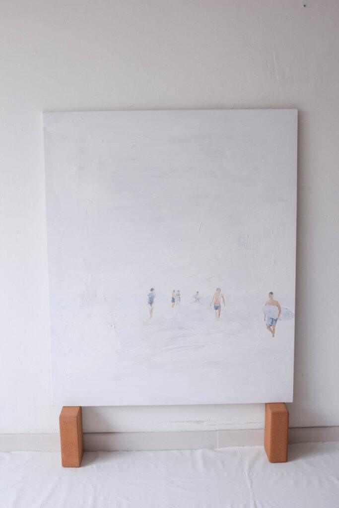 Opera figurativa minimalista di Alketa Delishaj, donna in riva al mare tra luce e vento.